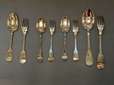 a lot of spoons and forks lined up on a table