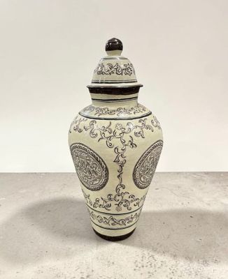une photo d'un vase blanc et noir posé sur une table