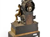a clock that is sitting on a stand with a figurine on top of it