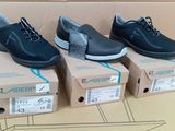 trois paires de chaussures noires sont posées sur une boîte en carton