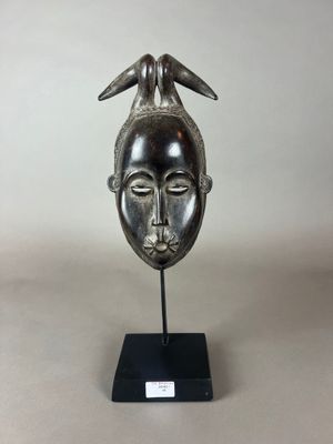 une sculpture en bronze représentant la tête d'une femme avec des cornes, posée sur un socle noir