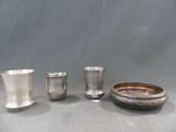 trois tasses en argent et un bol posés sur une table