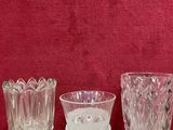 trois vases en verre posés sur une table en bois, près d'un mur rouge