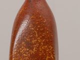 a brown vase sitting on a table with a white wall in the background