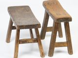 deux tabourets en bois placés l'un à côté de l'autre sur une surface blanche