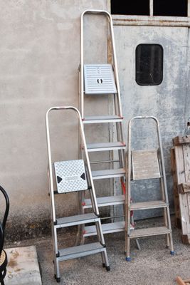 Plusieurs échelles sont appuyées contre un mur devant un immeuble.