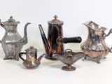 three silver teapots and a coffee pot on a table