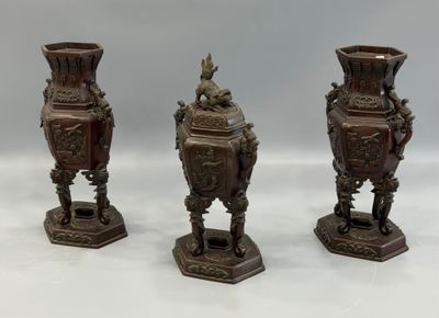 three antique bronze vases sitting on top of a white table