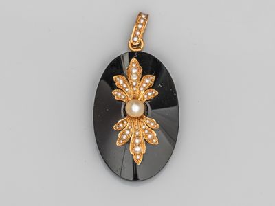 un pendentif noir et doré orné d'une fleur en perle