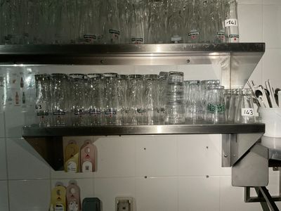 Des bouteilles et des verres sont empilés sur une étagère dans une cuisine.