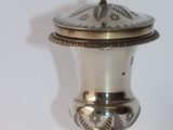 a silver vase with a bird on top of it