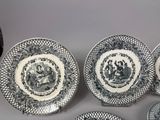 four plates with black and white designs on them sitting next to a vase
