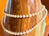 pearl necklace and bracelet on a wooden stand on a table