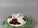 a green bowl with cherries in it on a table
