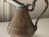 a silver pitcher sitting on a table next to a window