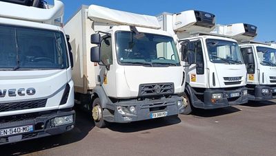 several white trucks are lined up in a row in a parking lot