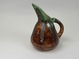 a brown and green pitcher sitting on a white surface