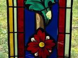 a stained glass panel with a flower and leaves on it