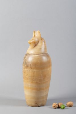 un vase en bois orné d'un oiseau, à côté de noix