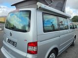 a silver van parked in a parking lot with a tent on top of it