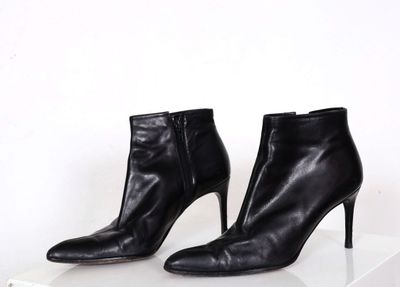 paire de bottes à talons hauts en cuir noir sur une surface blanche