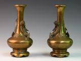 two bronze vases sitting side by side on a table