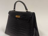 a black crocodile skin handbag on a white background