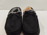 une paire de pantoufles noires doublées de fourrure, posées sur un fond blanc