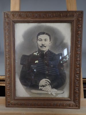 portrait of a man in a military uniform sitting in front of a wooden easel