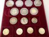 an assortment of silver coins in a red case on a white surface