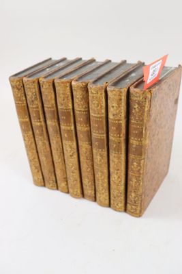 six vieux livres sont empilés sur une surface blanche
