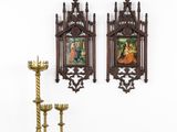 two ornate wooden wall hangings on a white wall above a table