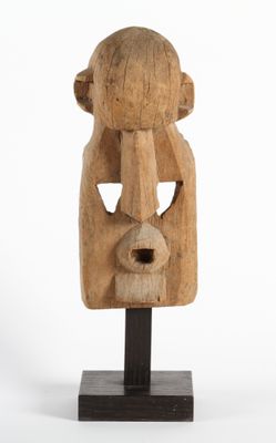 une photo d'une sculpture en bois représentant le visage d'un homme, posée sur un socle