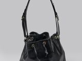 un sac seau en cuir noir posé sur une surface blanche