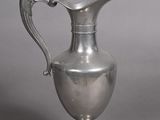 a silver pitcher with a handle on a table