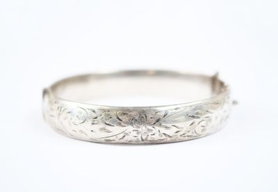 gros plan d'un bracelet en argent sur une surface blanche