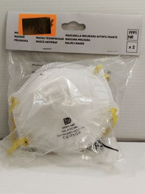 emballage d'un masque facial dans un sachet en plastique posé sur une surface blanche