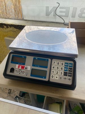 une image représentant une balance posée sur une table, avec une boîte en arrière-plan
