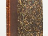 an old book with a brown cover sitting on top of a table