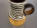 a black and white striped vase with a wooden handle