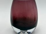 purple glass vase on a white table with a white background