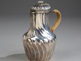 a silver and gold vase with a handle on a table