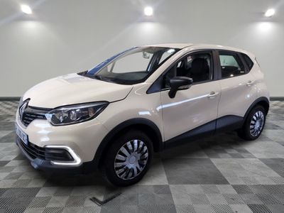 Une voiture blanche est garée sur un sol à damier dans une pièce.
