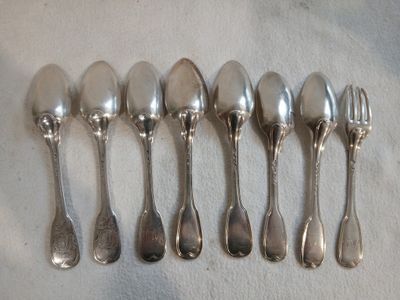 six cuillères en argent sont alignées sur une table