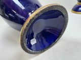 a blue vase with a gold rim sitting on a table