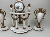 three vases and a clock sitting on a table