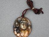 a close up of a necklace with a picture of a woman on it