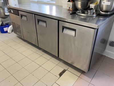 un grand plan de travail en inox dans une cuisine, sur lequel sont posées des casseroles et des poêles