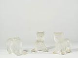 three white figurines of dogs sitting on a white surface