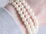 a close up of a person wearing a bracelet with pearls on it
